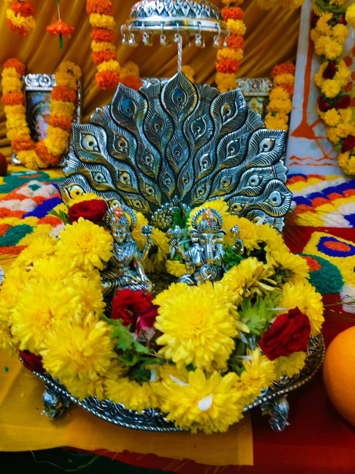 Lakshmi and Ganesh in a flower-covered tray at a home puja